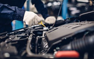 Auto car repair service center. Mechanic checking engine oil level