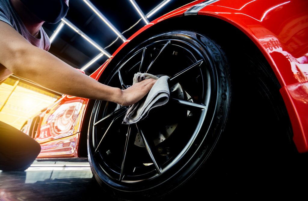 Car service worker polishing car wheels with microfiber cloth. Oil Change Burlington, WI