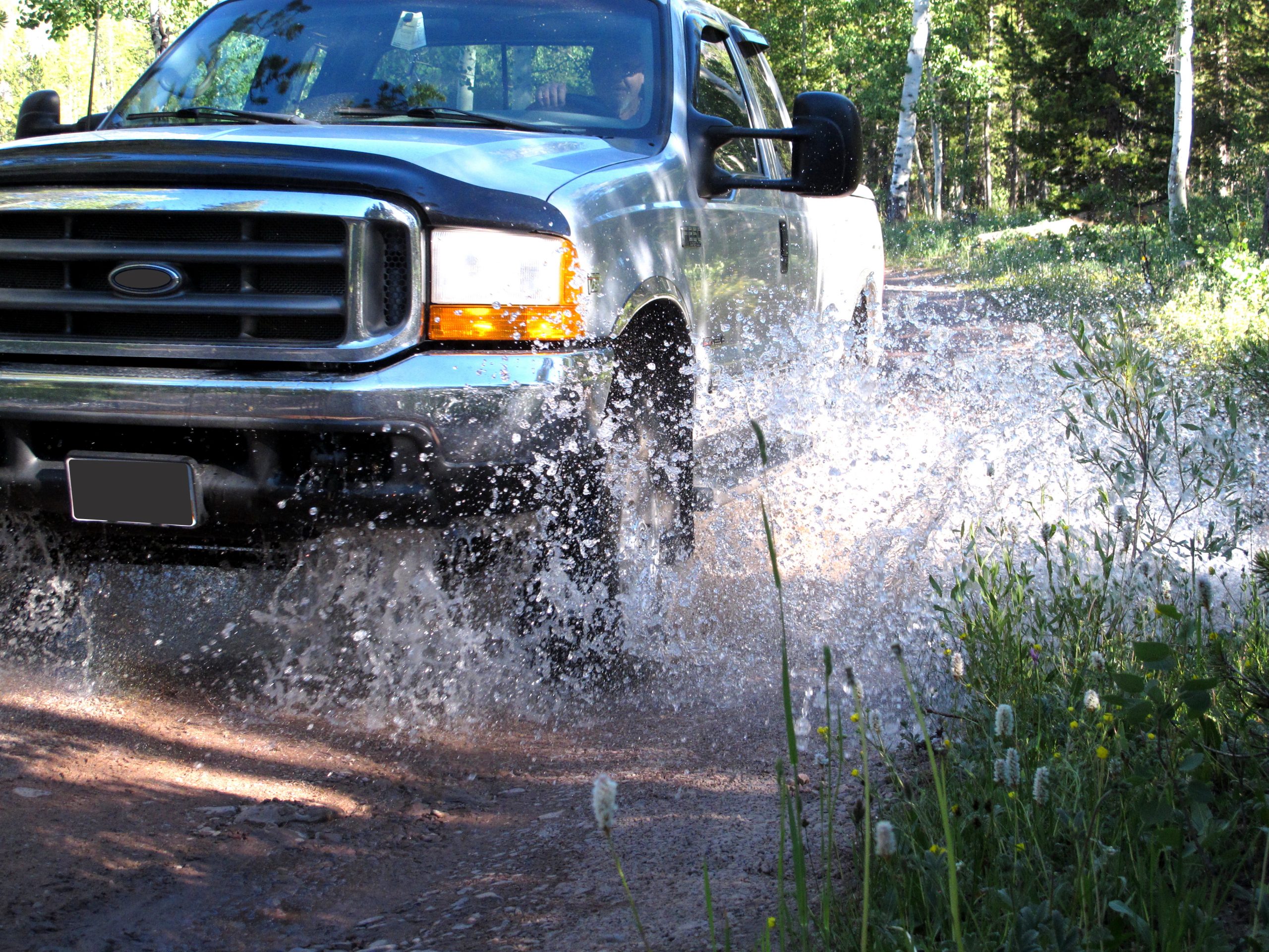 Silver Four Wheel Drive Pick Up Truck Splashing Through Mountain Stream Bed